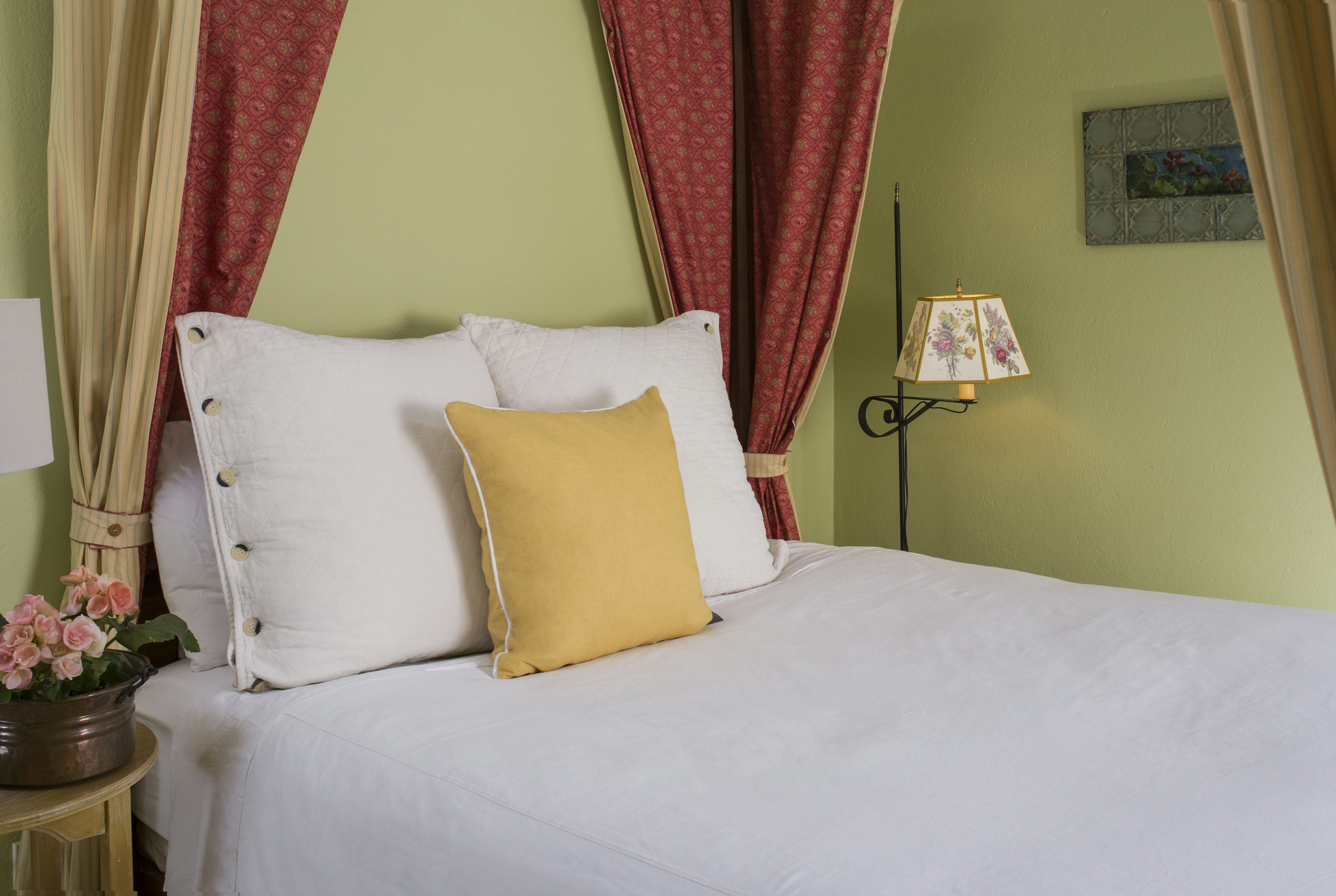 Close up of four-poster canopy bed with white bedding and decorative pillows