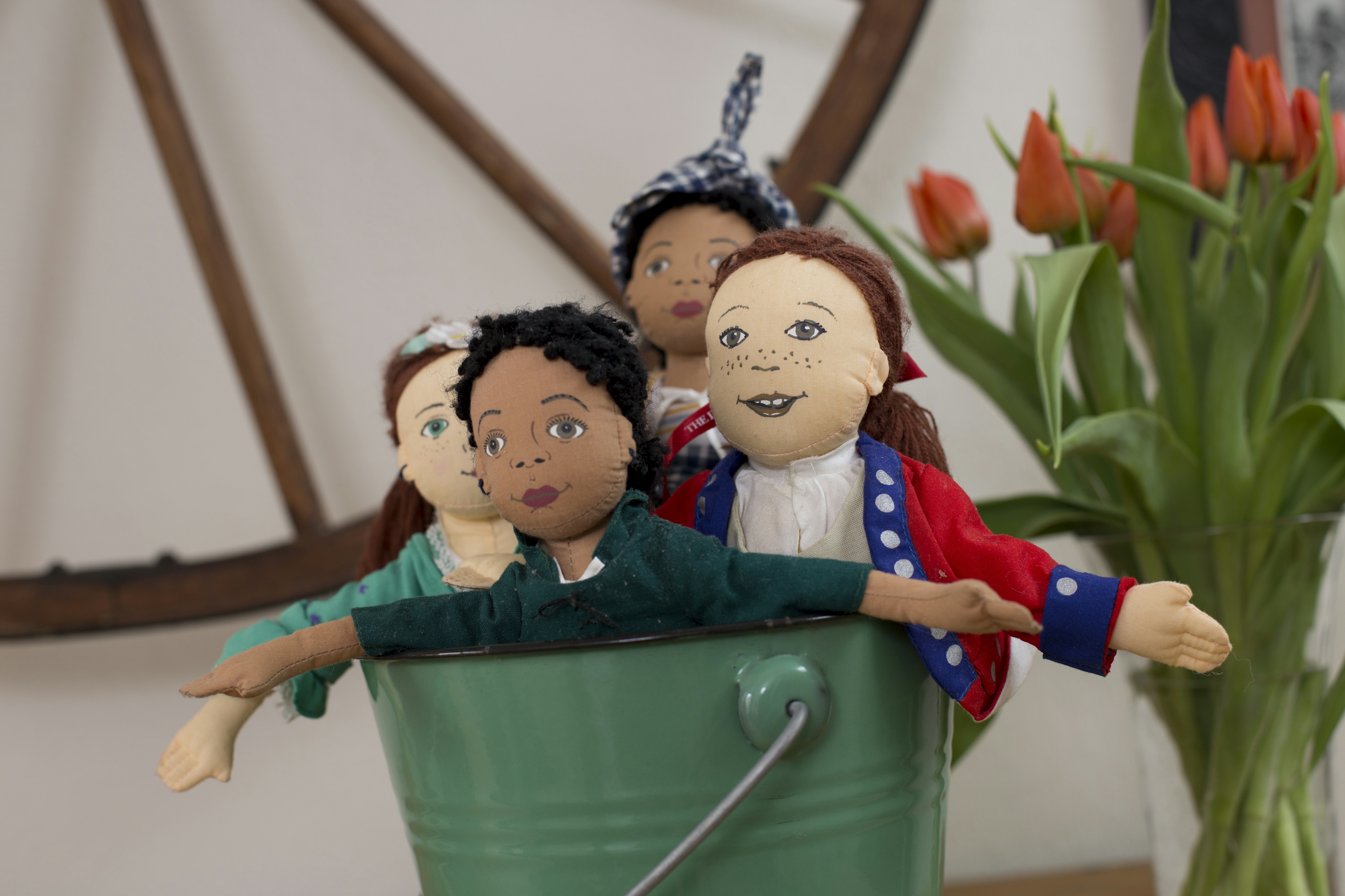 Metal bucket with four dolls inside dressed in colonial garb