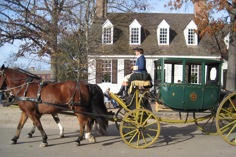 Man in period dress driving green carriage with brown horse