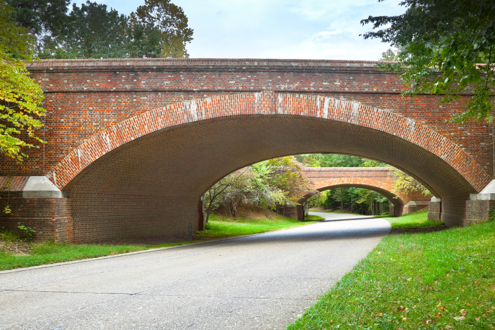 Colonial parkway with green grass, and arched brick bridges above the road