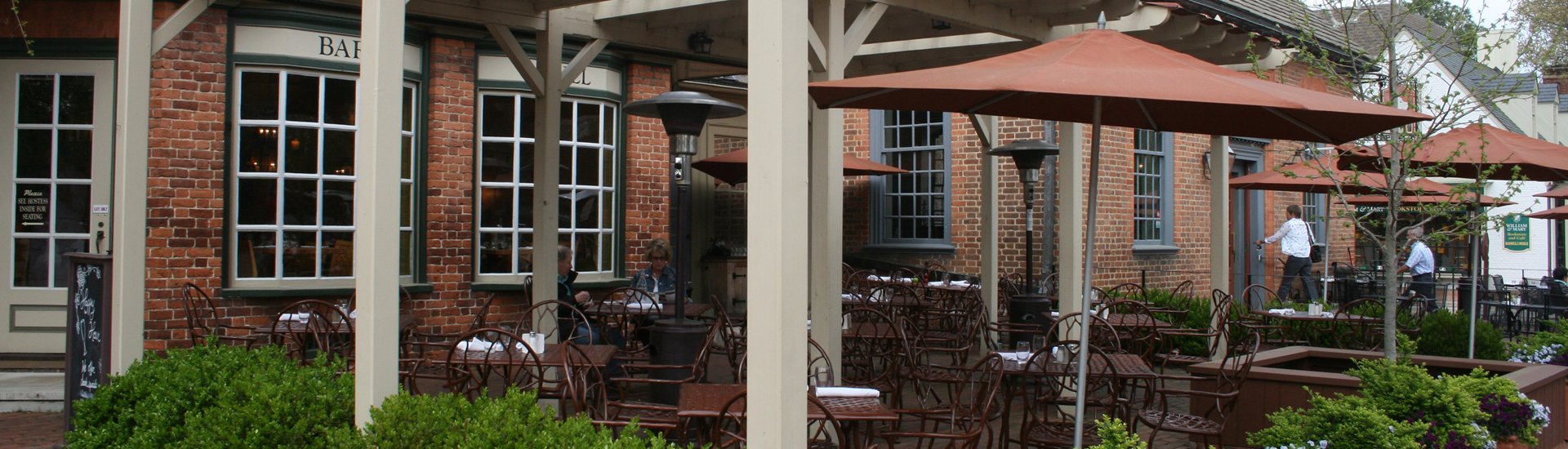 Black Iron Bistro tables outside in front of red brick building with white trim.