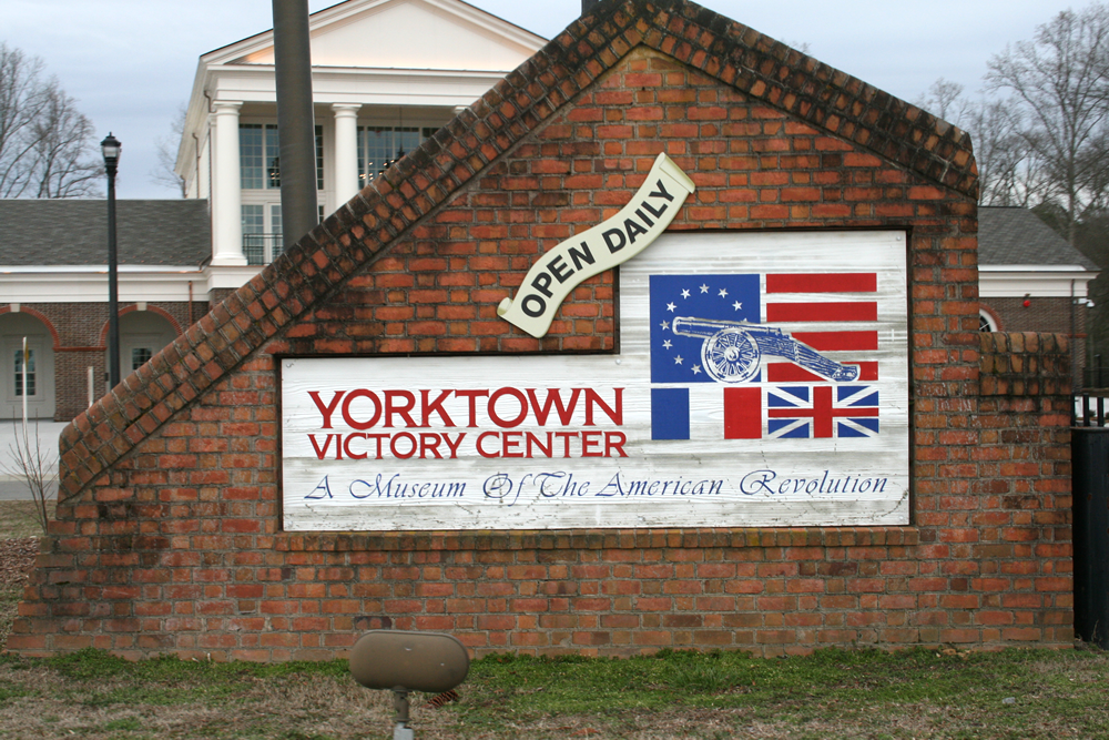 Yorktown victory center brick sign with wood inlay with name of center and open daily painted on it