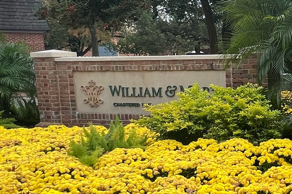 William and mary brick sign with yellow flowers in front