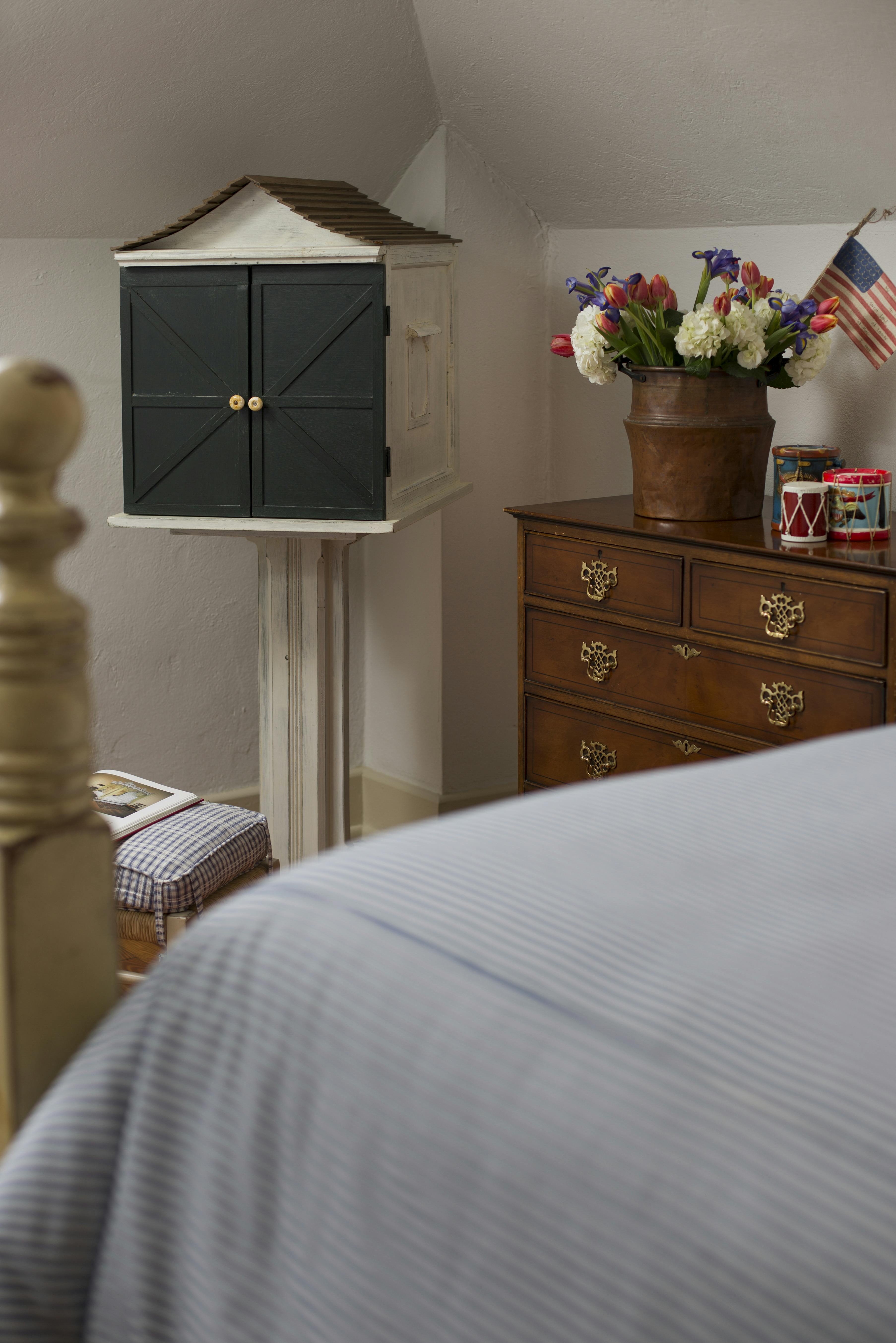 Bureau near foot of bed with red white and blue flower arrangement