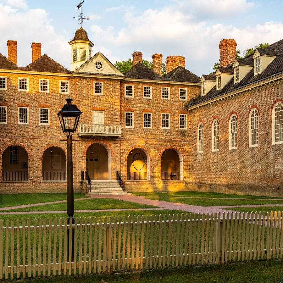 A multi winged yellow brick building with a grassy area in the middle