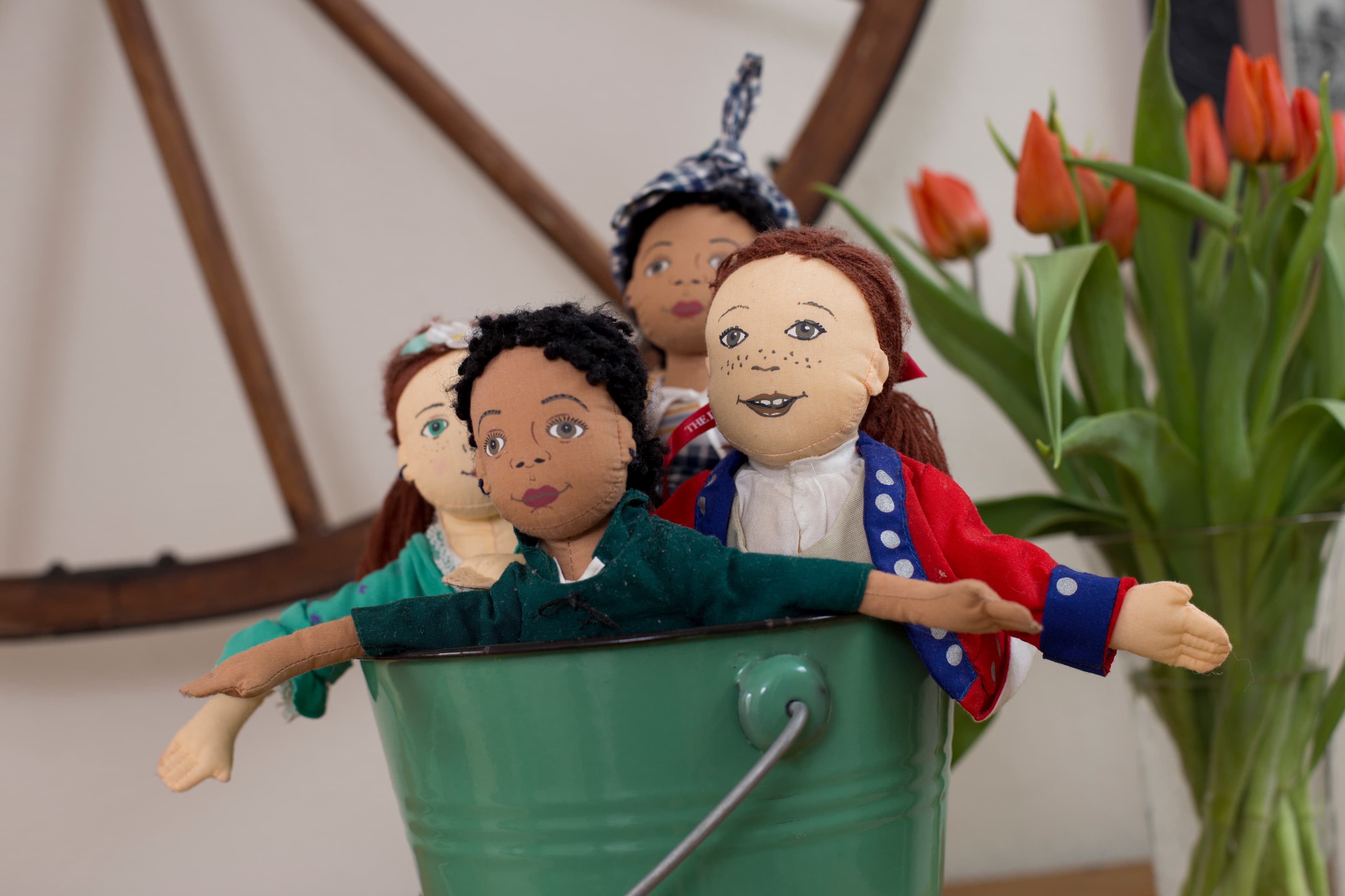 Metal bucket with four dolls inside dressed in colonial garb