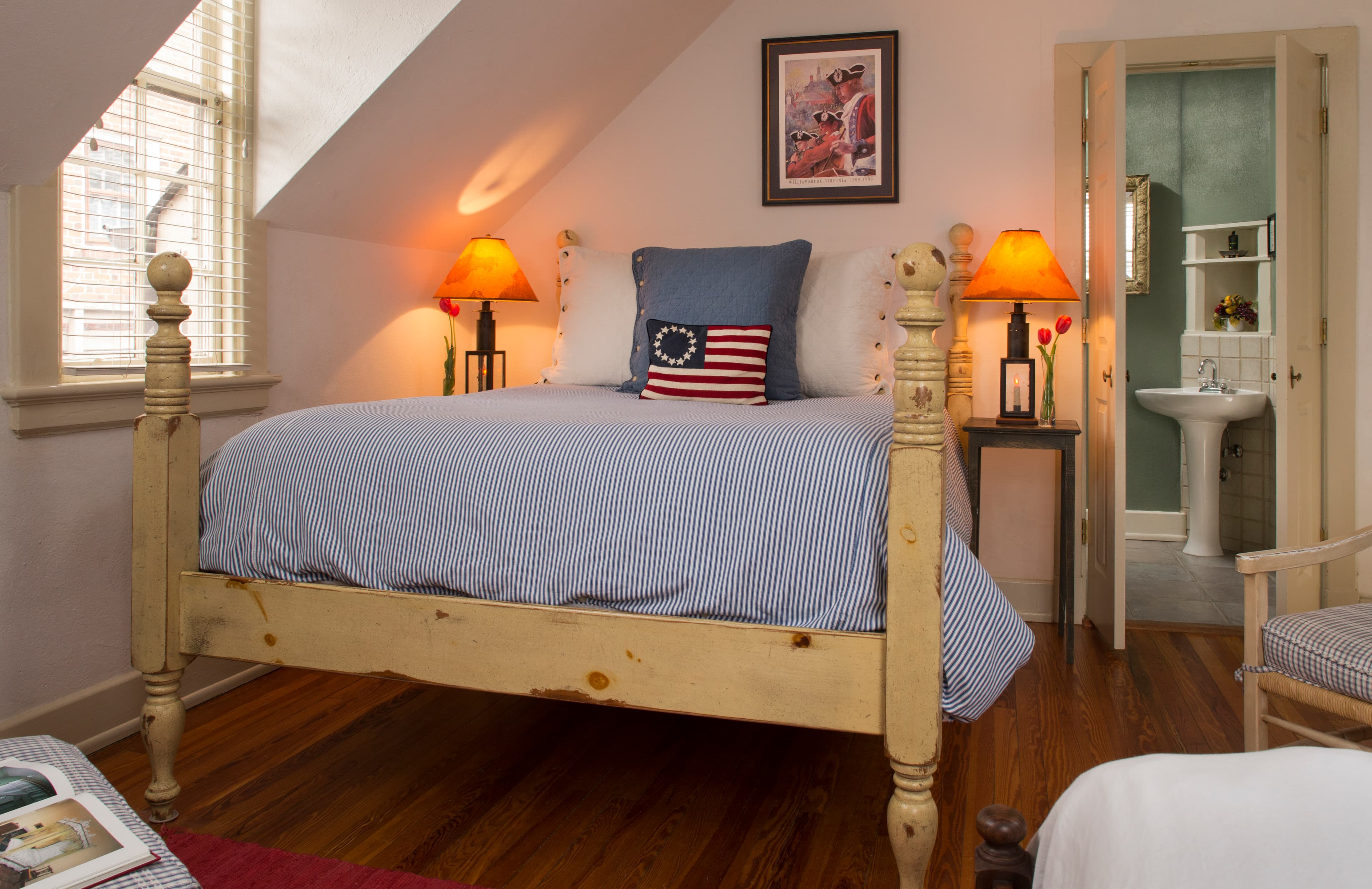 Painted distressed wooden bed with decorative pillows and doorway into bathroom