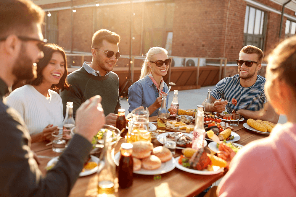 People sitting around a wood picnic table eating and drinking