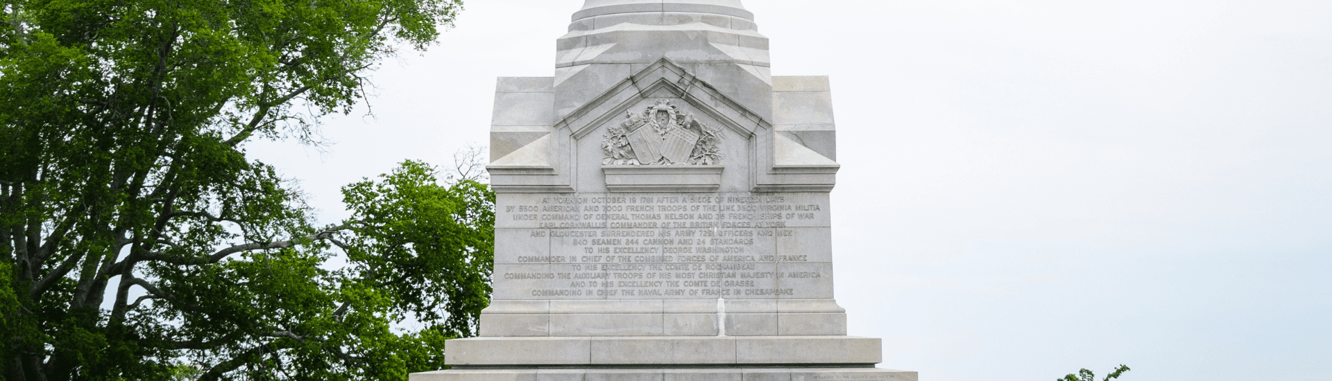 A multi winged yellow brick building with a grassy area in the middle