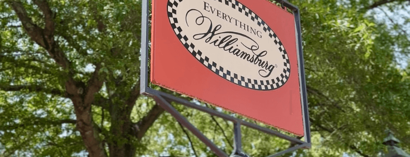 Sign for "Everything Williamsburg" surrounded by greenery. Sign for "Everything Williamsburg" surrounded by greenery.