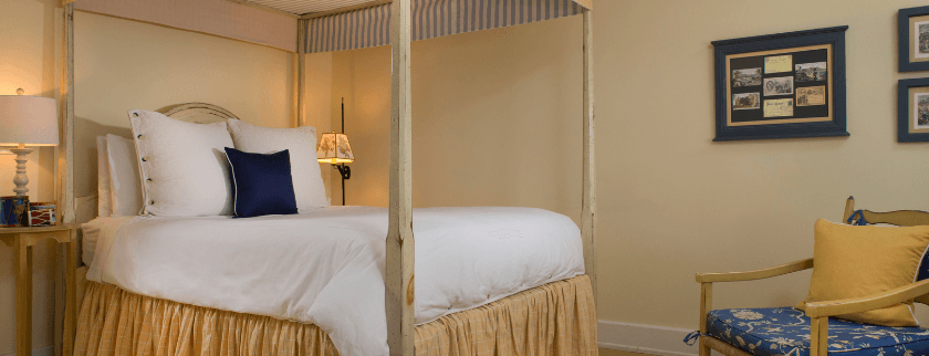 Cozy bedroom featuring a four-poster bed, armchair, and decorative wall frames.