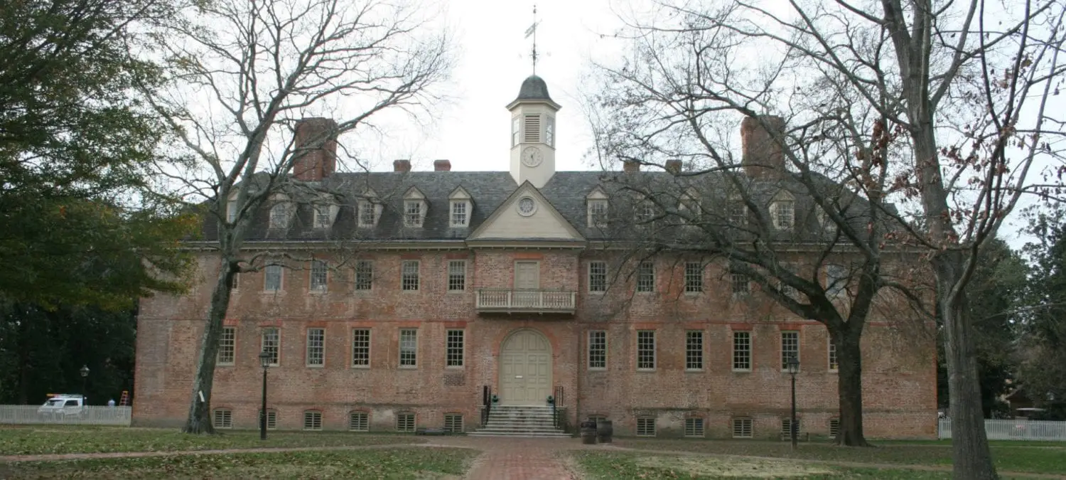 Historic brick building with a clock tower and surrounding bare trees.