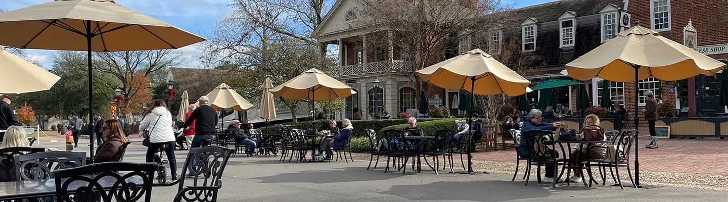A busy outdoor café with patrons sitting at tables under yellow umbrellas. A busy outdoor café with patrons sitting at tables under yellow umbrellas.