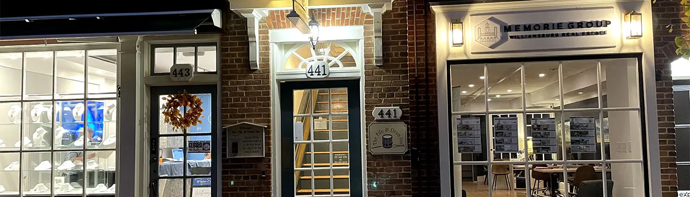 Nighttime exterior of brick storefronts with illuminated signs for businesses at 441 and 443. Nighttime exterior of brick storefronts with illuminated signs for businesses at 441 and 443.