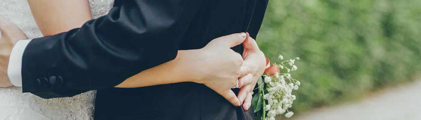 A couple embraces, with hands intertwined and a bouquet in view. A couple embraces, with hands intertwined and a bouquet in view.