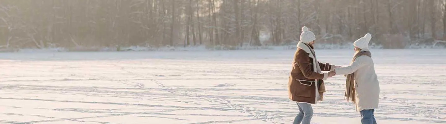 Two people skate playfully on a snowy landscape at sunset. Two people skate playfully on a snowy landscape at sunset.