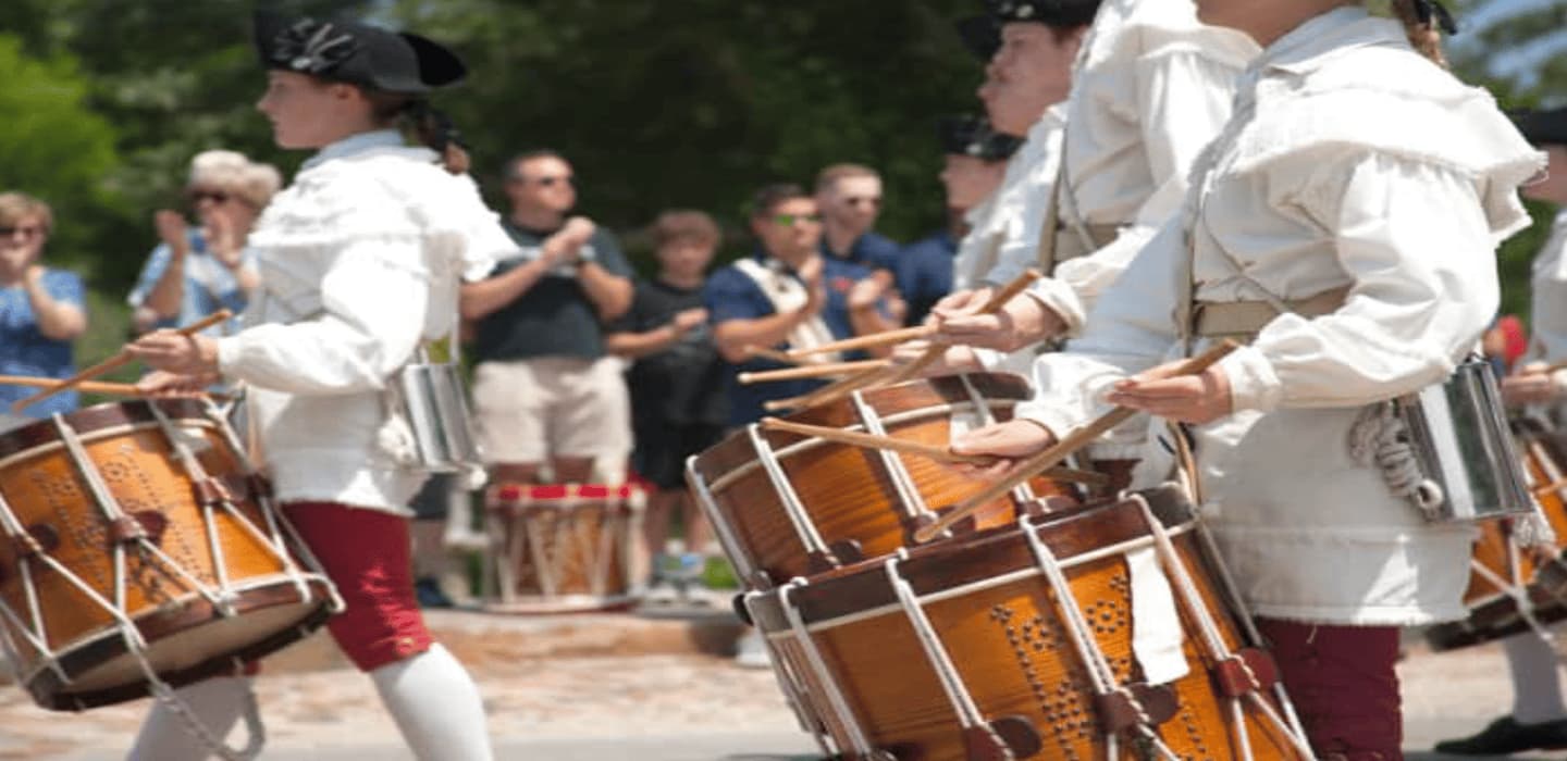 Drummers in historical attire perform during a lively outdoor event.
