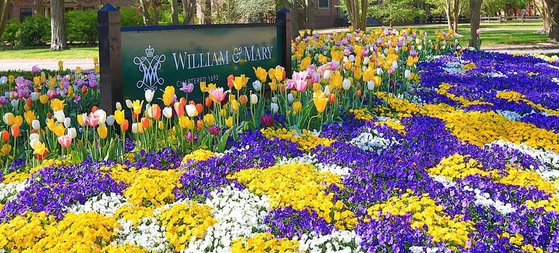Colorful flowerbeds surround a sign for William & Mary.