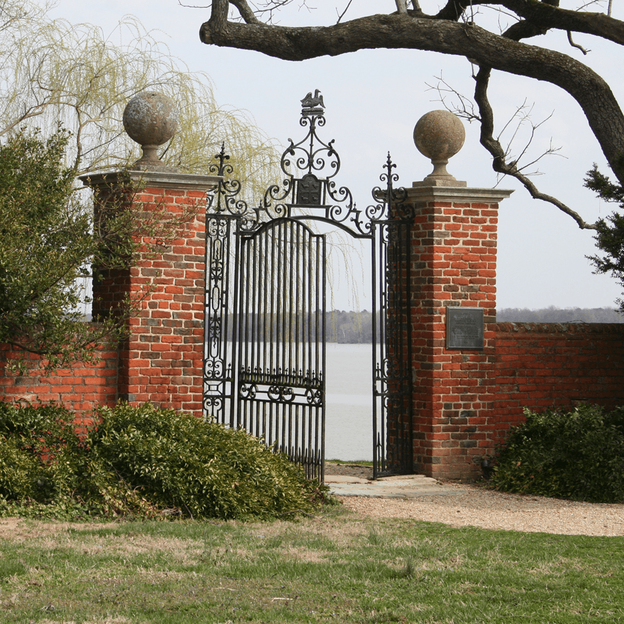 Two brick pillars with Iron Gates and cement round balls on top overlooking water