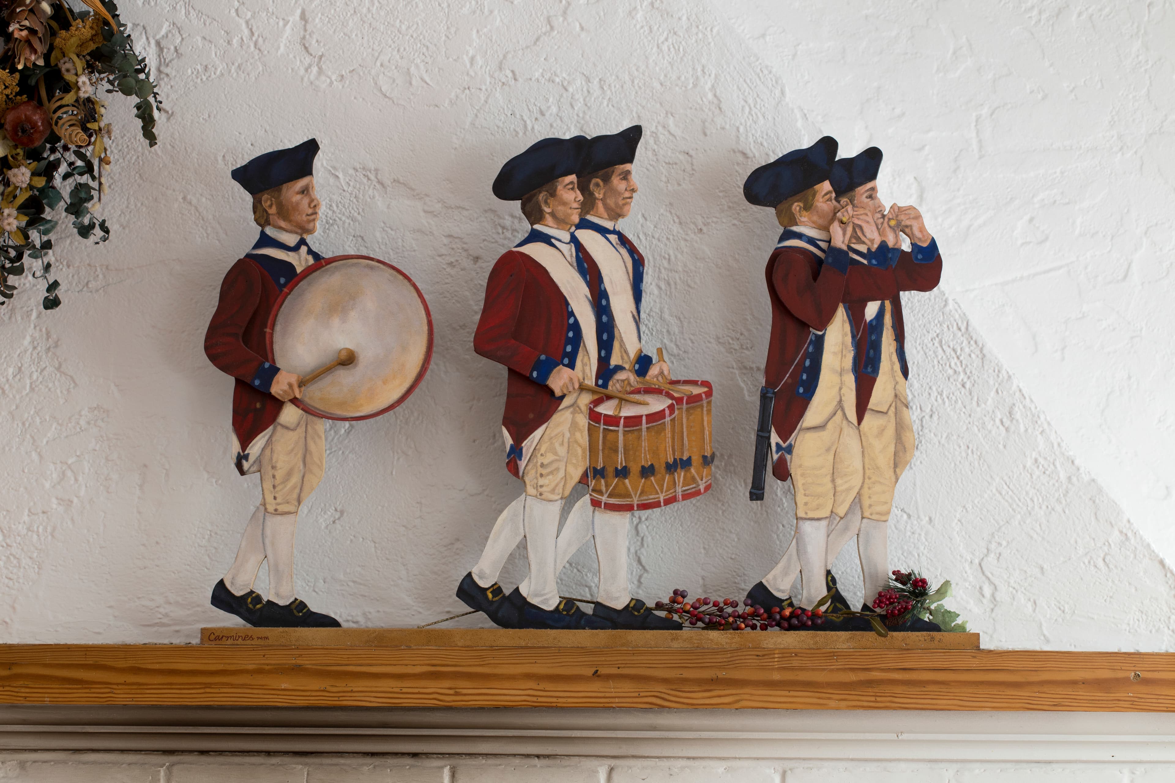 A mantle with wooden colonial soldiers playing fifes and drums.