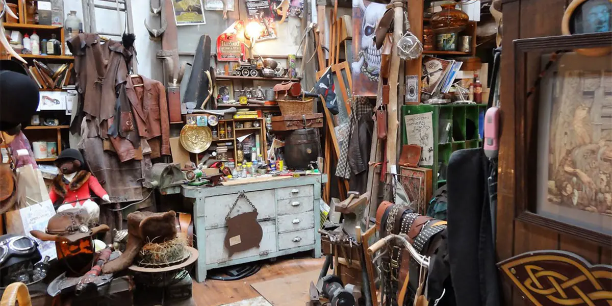 A cluttered antique shop filled with various items, including furniture, tools, and collectibles.
