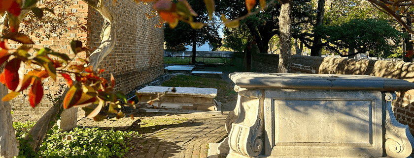 A serene cemetery pathway lined with tombs, surrounded by trees and autumn leaves. A serene cemetery pathway lined with tombs, surrounded by trees and autumn leaves.