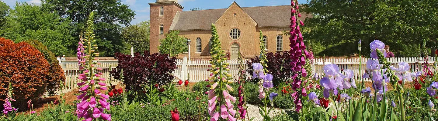 A vibrant garden filled with blooming flowers in front of a historic brick building.
