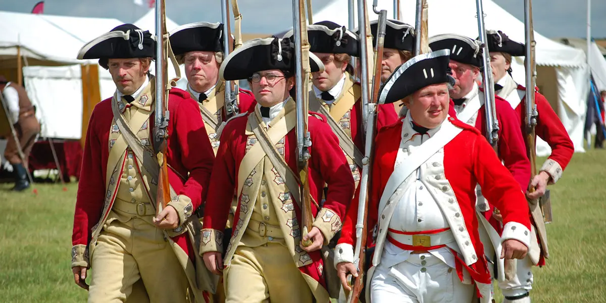 Soldiers in 18th-century military uniforms march in formation.