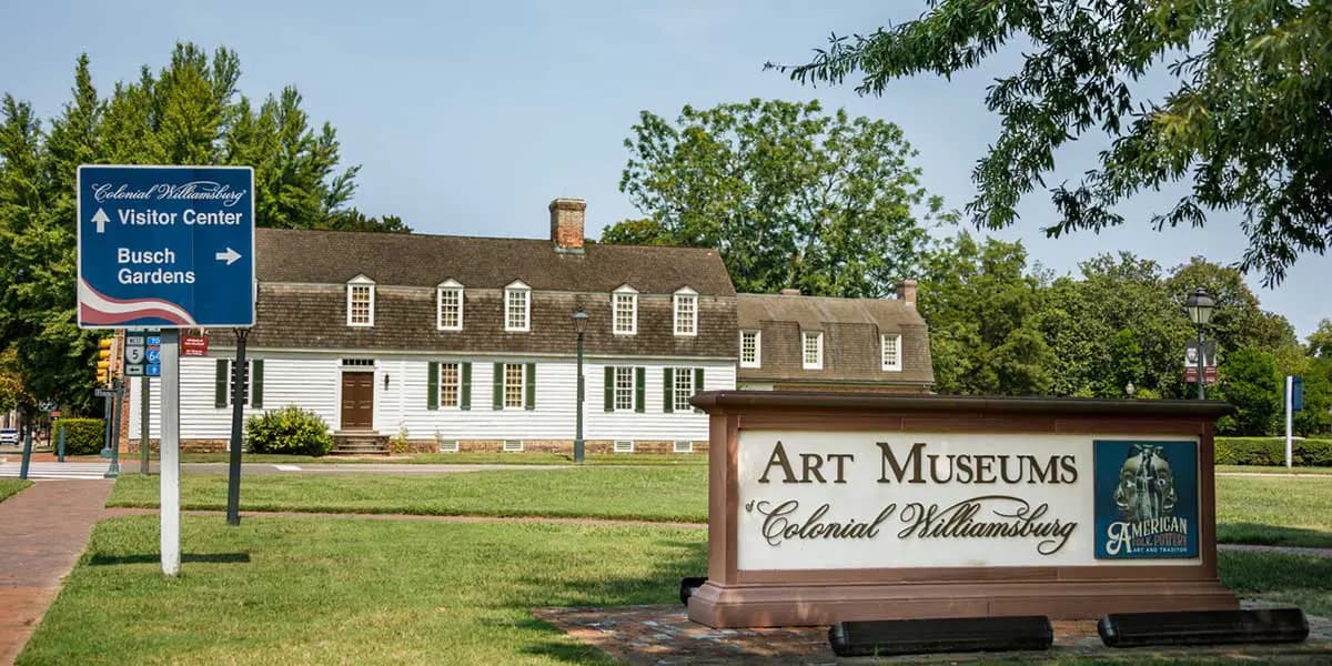 Signage for the Art Museums of Colonial Williamsburg with a historic building in the background.