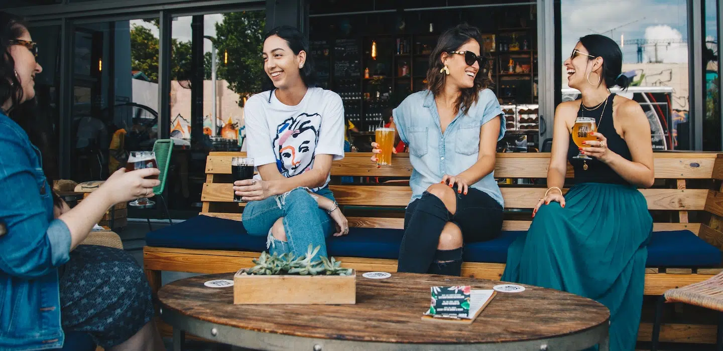 A group of four friends enjoys drinks together at an outdoor café.