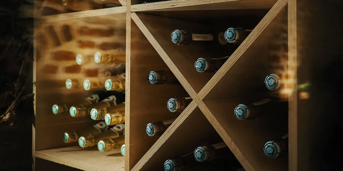 A wooden wine rack displaying several bottles with blue labels.