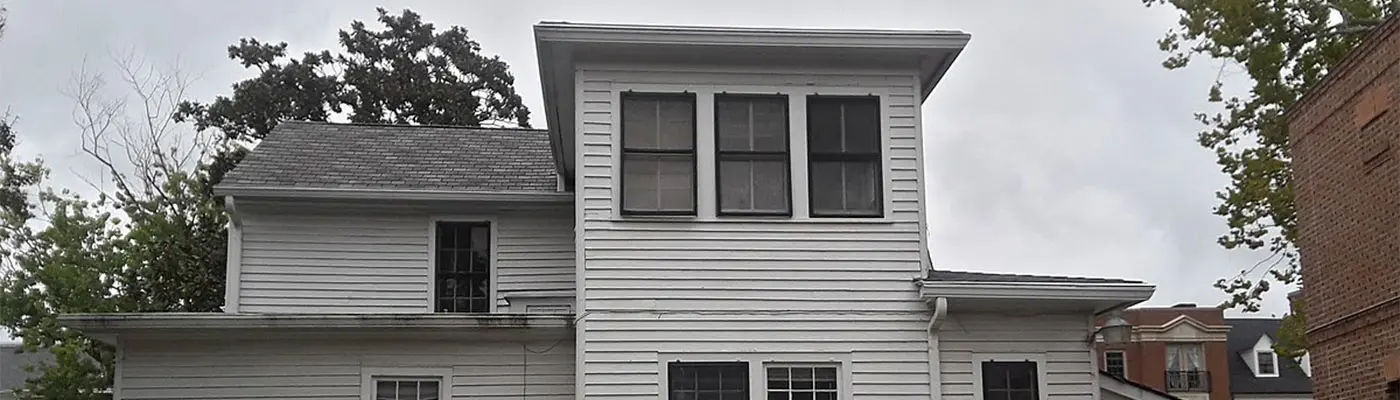 A white two-story house with multiple windows under a cloudy sky. A white two-story house with multiple windows under a cloudy sky.