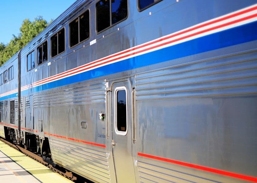 A silver train with blue and red stripes parked at a station. A silver train with blue and red stripes parked at a station.