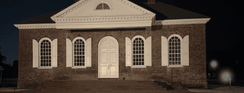 Historic brick building with white windows and door, illuminated at night.
